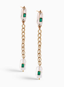 Aretes largos con esmeraldas en bruto y cuarzo, diseñados con cadenas doradas que aportan movimiento y sofisticación. Hechos a mano en bronce con baño de oro de 24K.