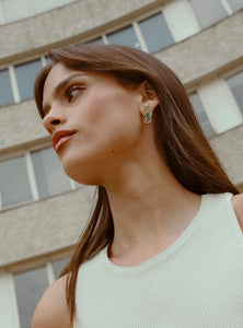 Aretes pequeños con esmeralda en bruto y cuarzo, una combinación perfecta de modernidad y elegancia. Hechos a mano en bronce con baño de oro de 24K, su diseño geométrico y sofisticado los convierte en el complemento ideal para cualquier ocasión.