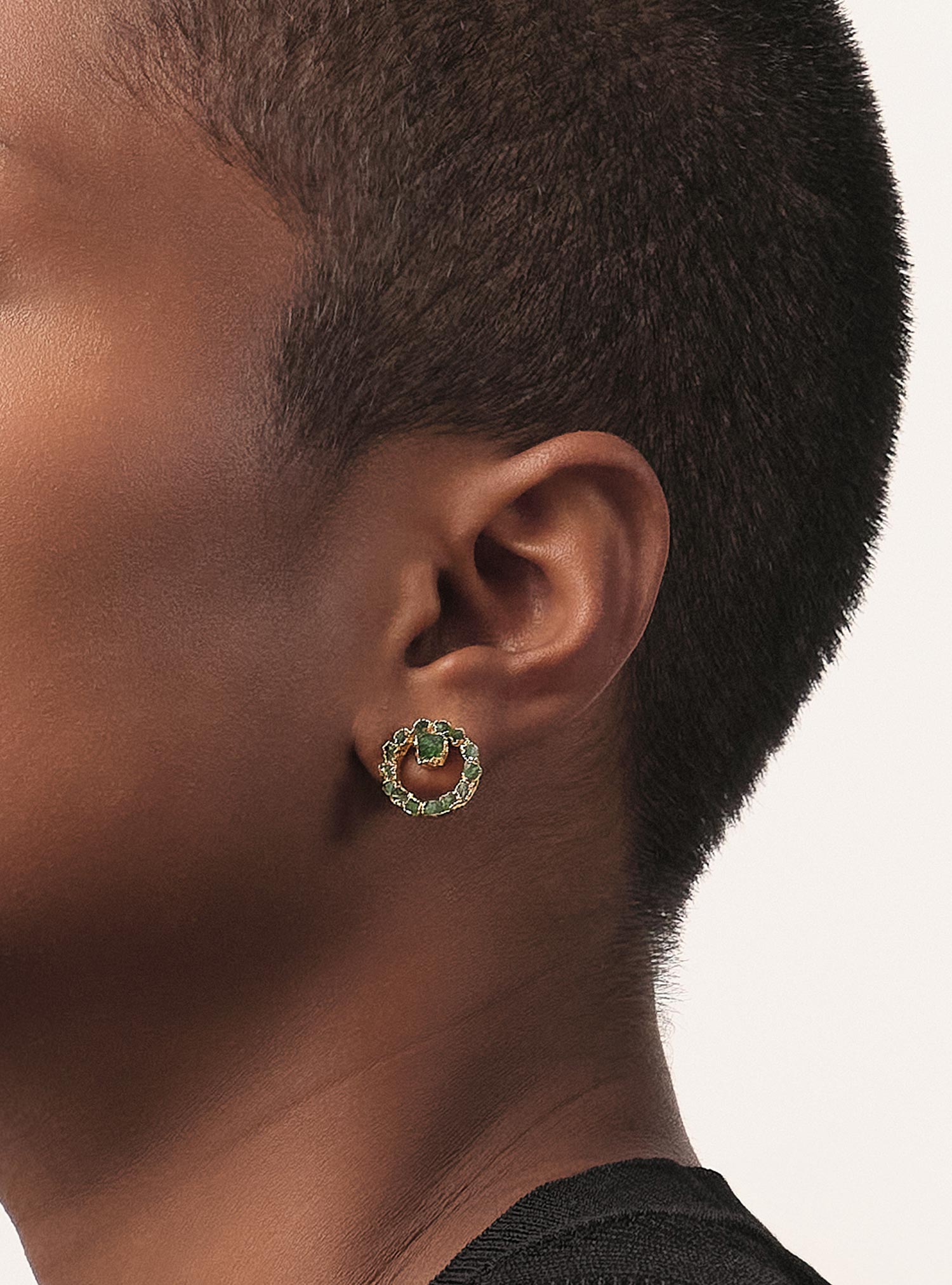 A raw emerald takes the spotlight — framed by a golden circle crafted en bronce con baño en oro. Una pieza que combina fineza, textura y carácter, ideal para elevar cualquier look con autenticidad y un toque moderno.