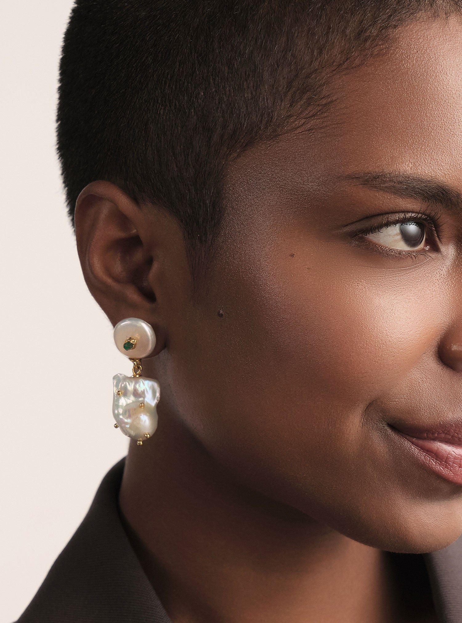 Aretes artesanales de perla barroca intervenida con esmeralda en bruto. Un diseño elegante y atemporal que resalta autenticidad y lujo.