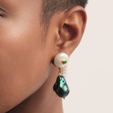 Aretes artesanales con perla blanca y perla barroca negra intervenida con esmeralda colombiana. Un diseño elegante y contemporáneo hecho a mano en Colombia.