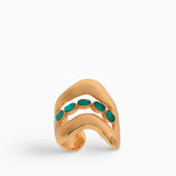 Ear cuff dorado con esmeraldas naturales, diseñado con líneas orgánicas que envuelven la oreja sin necesidad de perforación. Una pieza de joyería artesanal hecha a mano en bronce con baño de oro de 24K.