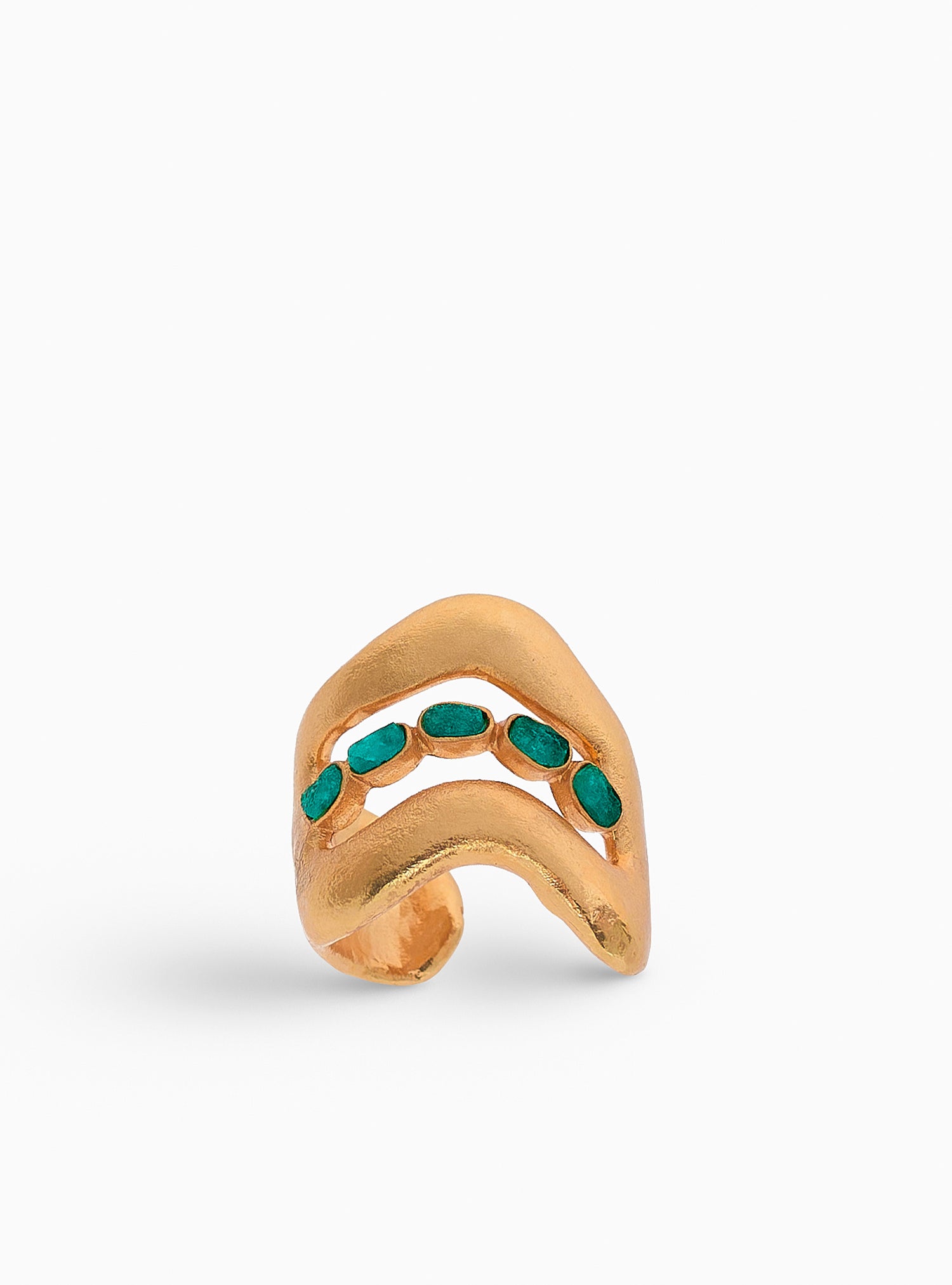 Ear cuff dorado con esmeraldas naturales, diseñado con líneas orgánicas que envuelven la oreja sin necesidad de perforación. Una pieza de joyería artesanal hecha a mano en bronce con baño de oro de 24K.