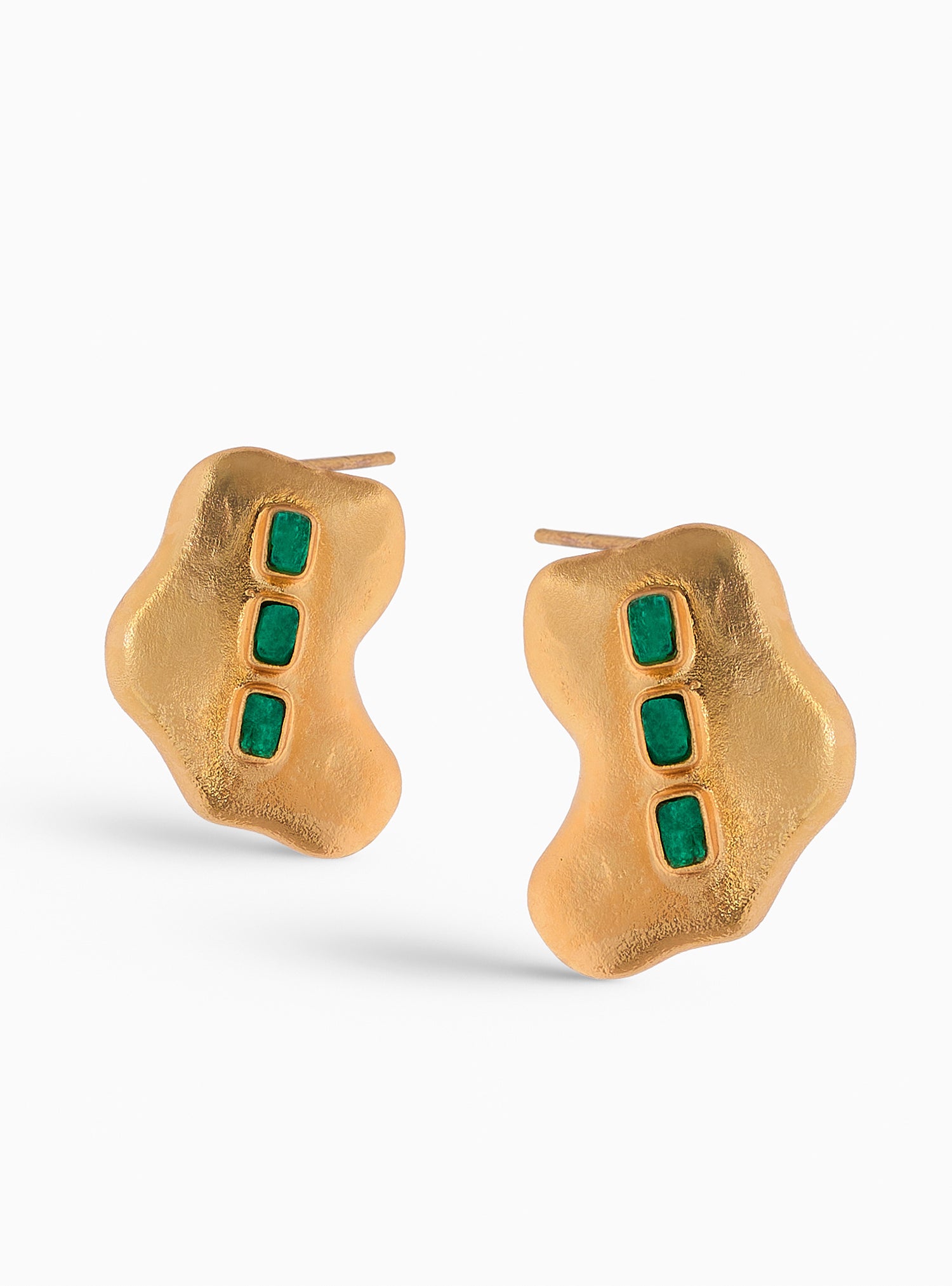 Aretes de diseño orgánico con esmeraldas colombianas incrustadas. Hechos a mano en bronce con baño de oro de 24K, estos pendientes combinan modernidad y elegancia en una pieza única.