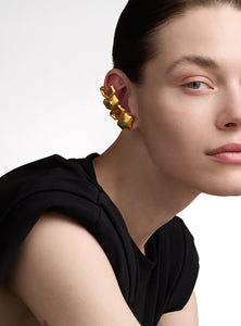 Ear climber dorado con esmeraldas naturales. Su diseño orgánico y artesanal, hecho a mano en bronce con baño de oro de 24K, lo convierte en una pieza única y versátil.