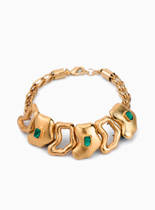 Pulsera artesanal con eslabones de bronce bañados en oro de 24K y detalles de esmeralda en bruto. Su diseño orgánico y escultural lo convierte en una pieza statement única, perfecta para quienes buscan joyas sofisticadas y atemporales.