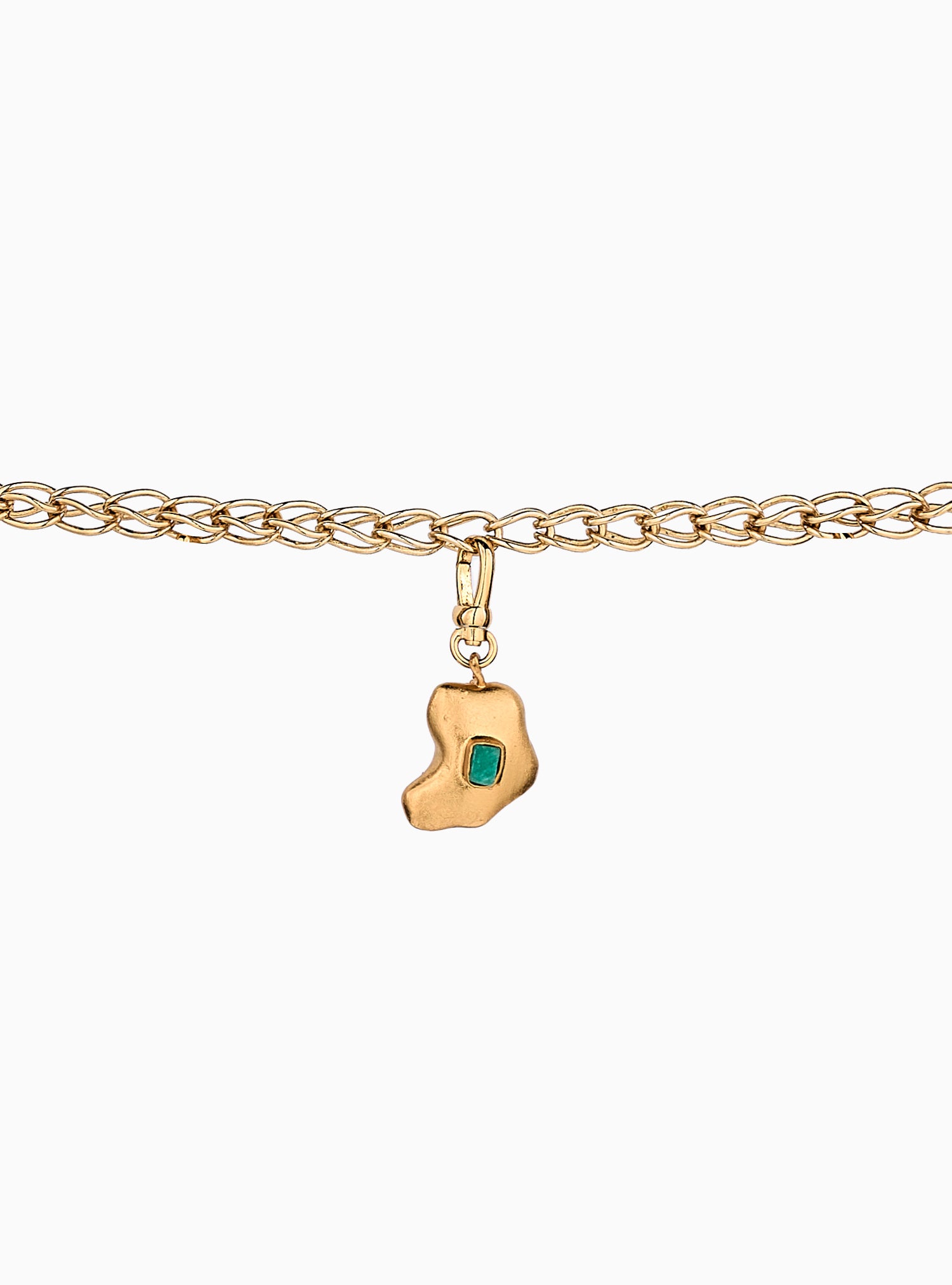 Charm artesanal con esmeralda en bruto incrustada y baño de oro de 24k. Un diseño orgánico y elegante que celebra la belleza natural de la piedra.