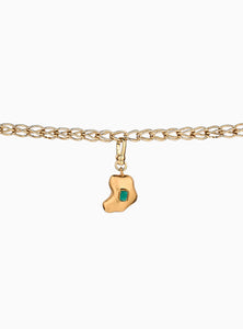 Charm artesanal con esmeralda en bruto incrustada y baño de oro de 24k. Un diseño orgánico y elegante que celebra la belleza natural de la piedra.
