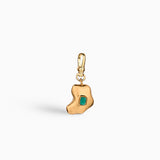 Charm artesanal con esmeralda en bruto incrustada y baño de oro de 24k. Un diseño orgánico y elegante que celebra la belleza natural de la piedra.