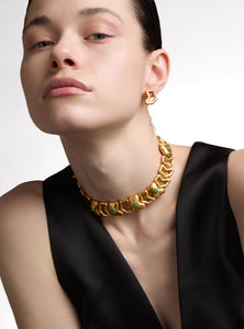 Collar artesanal con eslabones de bronce bañados en oro de 24K y detalles de esmeralda en bruto. Su diseño orgánico y escultural lo convierte en una pieza statement única, perfecta para quienes buscan joyas sofisticadas y atemporales.