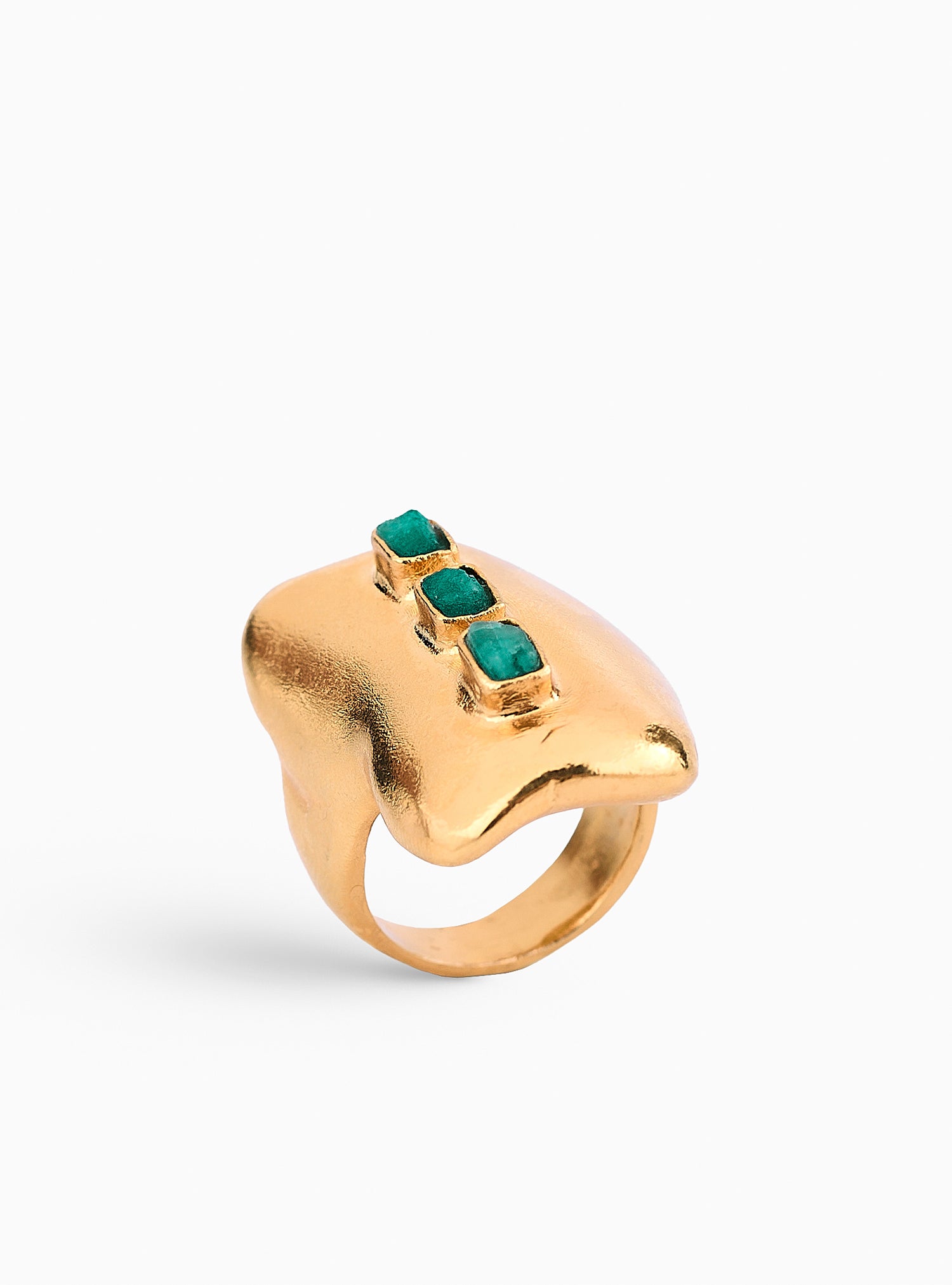 Anillo dorado con esmeraldas en bruto, diseñado con una estructura orgánica que fusiona modernidad y artesanía. Hecho a mano en bronce con baño de oro de 24K, una joya única y atemporal.