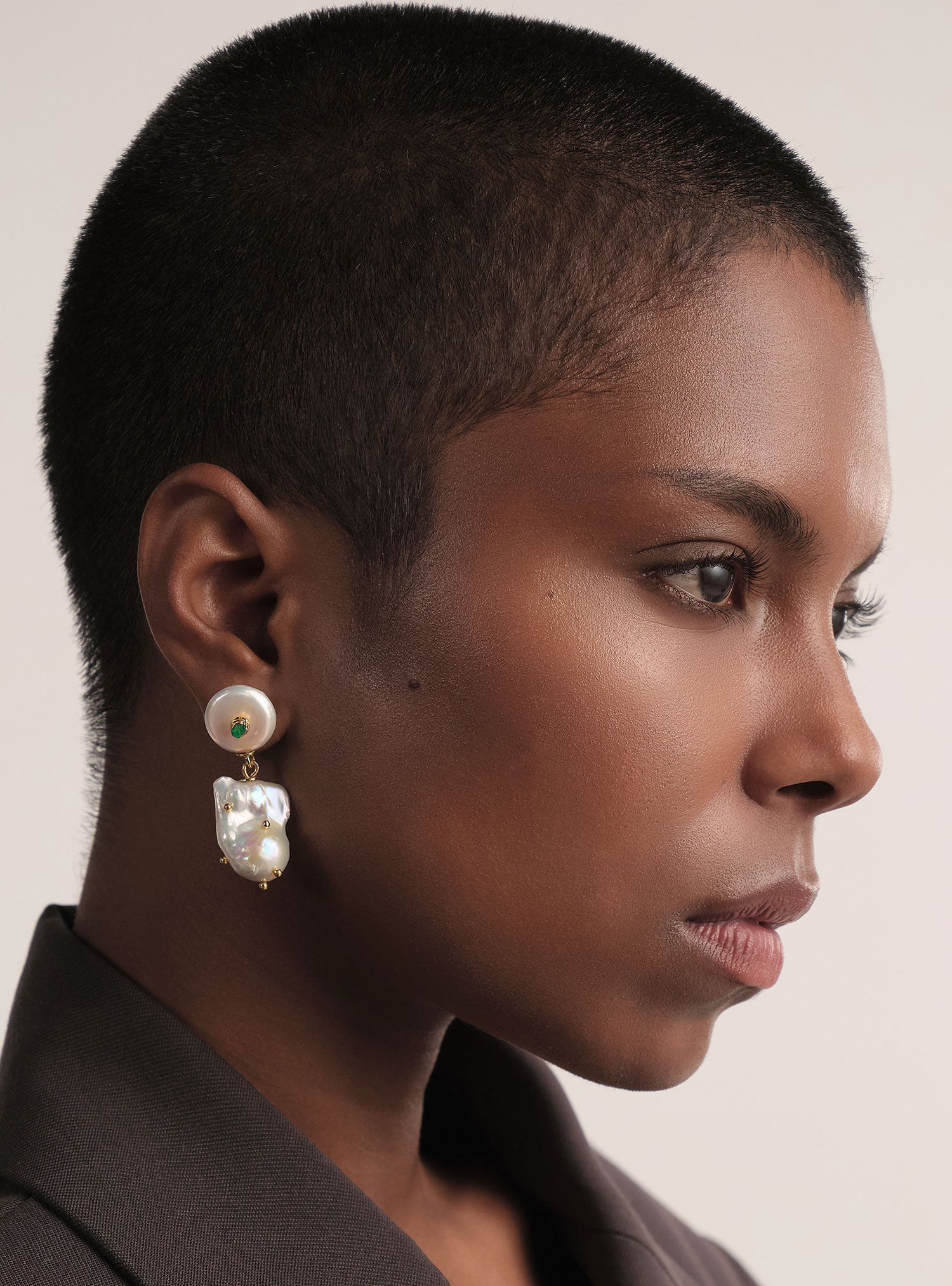 Aretes de perla barroca con esmeralda colombiana en bruto, hechos a mano en bronce con baño de oro. Joyería artesanal de Colombia con estilo único.