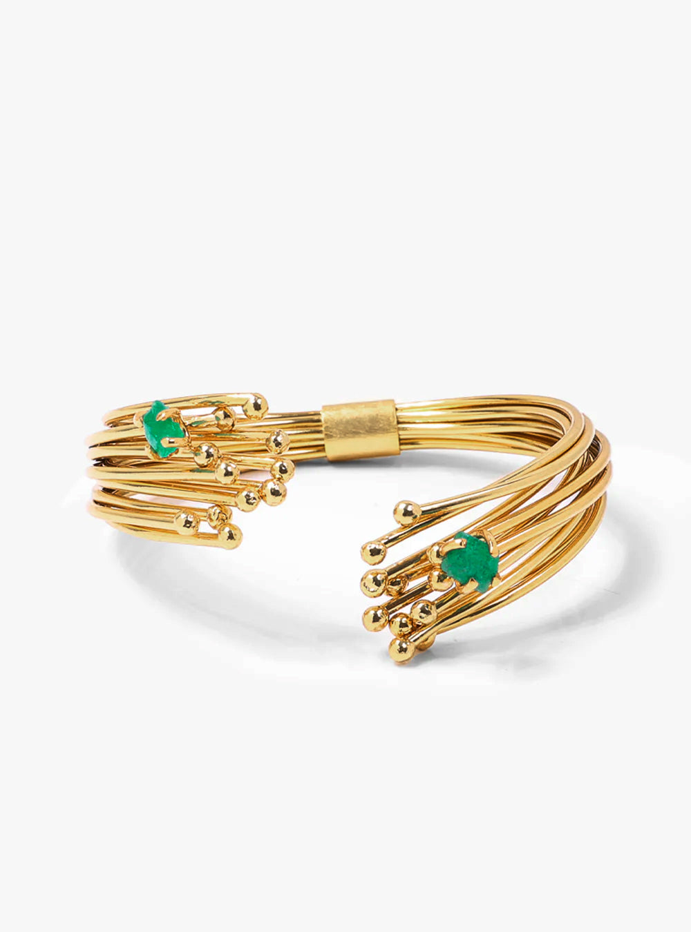 Pulsera contemporánea compuesta por capas de hilos dorados en bronce con baño en oro, curvados y ensamblados artesanalmente para lograr un acabado impecable. Dos esmeraldas crudas emergen entre los hilos como gemas protagonistas, aportando textura, rareza y carácter. Esta imagen resalta una pieza de joyería elevada, de manufactura meticulosa y con un lenguaje escultórico que representa la identidad más sofisticada de Fenomena.